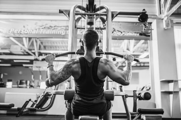 Arka üstünde makine için ağır egzersiz yaparak güçlü vücut geliştirmeci