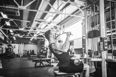 Arka üstünde makine için ağır egzersiz yaparak güçlü vücut geliştirmeci