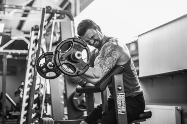 Bir spor salonunda bir halter egzersiz kümesi yapıyor adam vücut geliştirmeci.