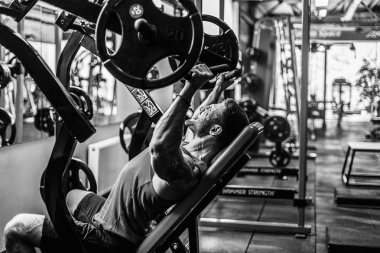 Simülatörde omuzlar için bir egzersiz yapan erkek