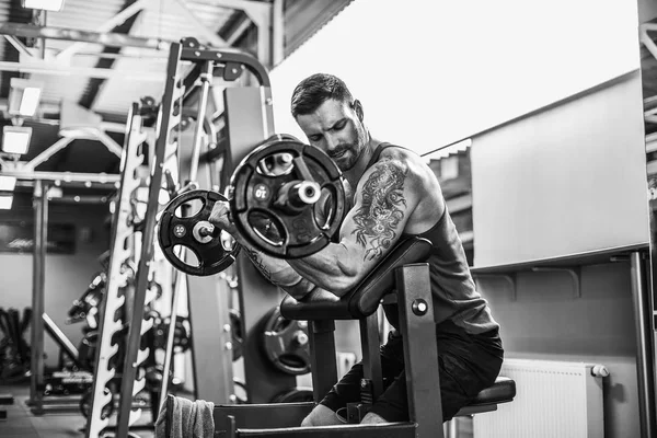 Hombre culturista haciendo el conjunto de un ejercicio de barra en un gimnasio . —  Fotos de Stock