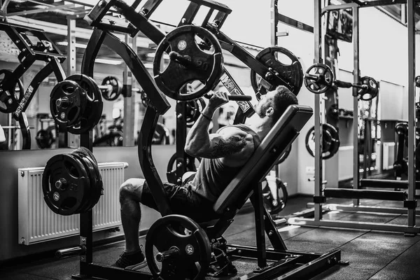 Simülatörde omuzlar için bir egzersiz yapan erkek