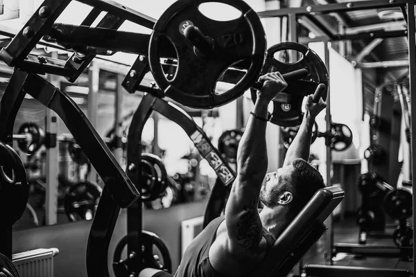 Simülatörde omuzlar için bir egzersiz yapan erkek