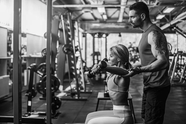 Sportif kız Yardımı salonunda kişisel onu antrenman ör ile ağırlık egzersizleri yapıyor.