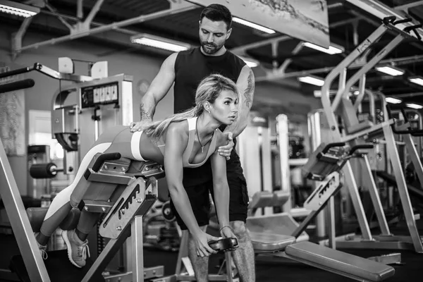 运动型的协助下她的私人教练在健身房锻炼重量. — 图库照片