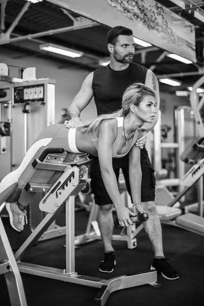 Sportovní holka dělá váha cvičení s pomocí její osobní trenér v posilovně. — Stock fotografie