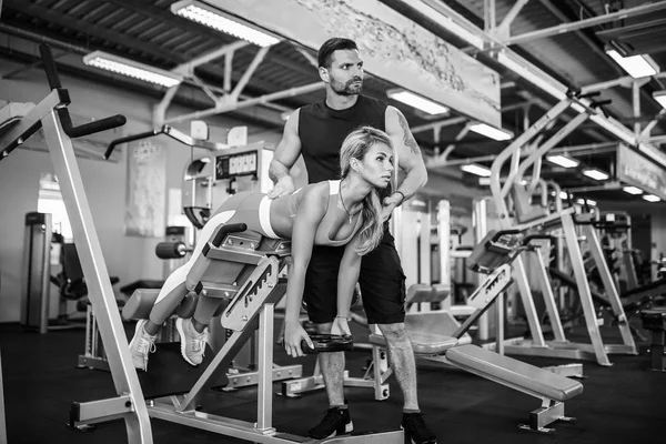 Chica deportiva haciendo ejercicios de peso con la ayuda de su entrenador personal en el gimnasio . —  Fotos de Stock