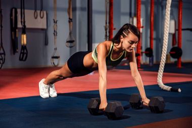 Çekici genç kadın spor yaparken kalas egzersizi yapıyor.