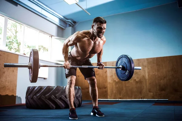 Jeune homme dans une salle de gym Crossfit soulevant un haltère . — Photo