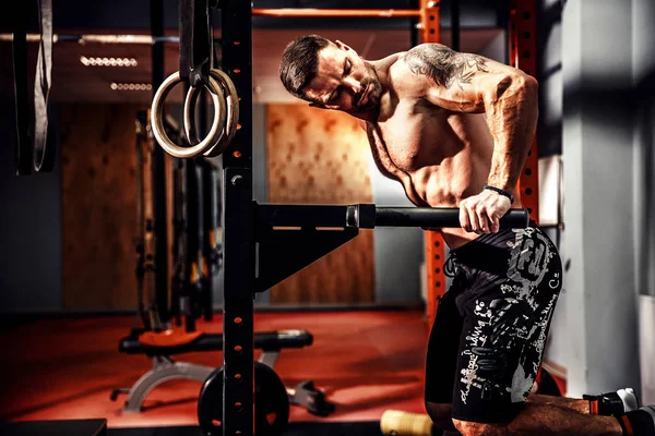 Sterke gespierde man doen push-ups op ongelijke liggers in crossfit gym — Stockfoto