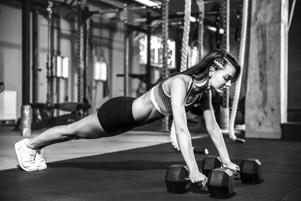 Attrayant jeune femme fait de l'exercice de planche tout en travaillant dans la salle de gym — Photo