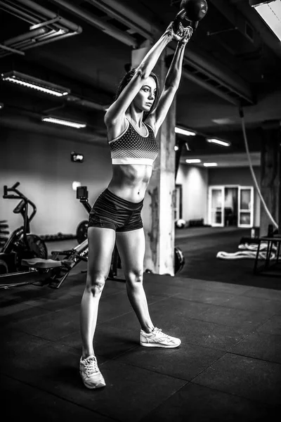 Attractive female athlete performing a kettle-bell swing — Stock Photo, Image