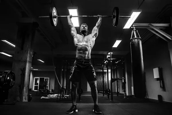 Hombre musculoso en un gimnasio crossfit levantando una barra. — Foto de Stock