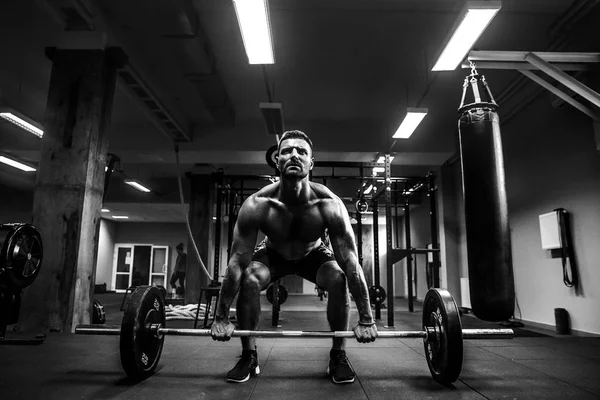 Hombre musculoso en un gimnasio crossfit levantando una barra. — Foto de Stock