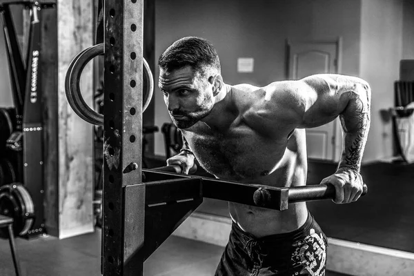 Starker muskulöser Mann macht Liegestütze auf unebenem Barren in Crossfit-Fitnessstudio — Stockfoto