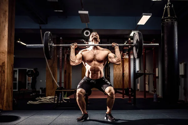 Muscular fitness hombre haciendo deadlift una barra sobre su cabeza en el moderno gimnasio. Entrenamiento funcional. — Foto de Stock