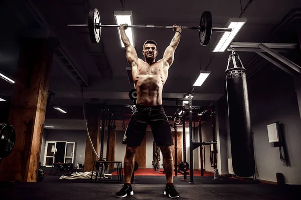 Homem de fitness muscular fazendo deadlift um sino sobre sua cabeça no moderno centro de fitness. Treinamento funcional. — Fotografia de Stock