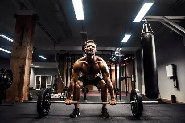 Muskelkräftiger Fitnessmann beim Kreuzheben einer Langhantel über dem Kopf in einem modernen Fitnesscenter. Functional Training. — Stockfoto