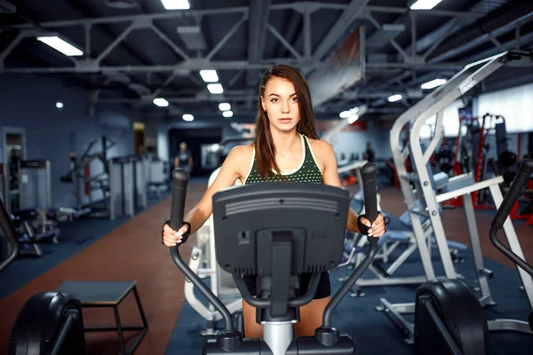 Junge Fitness-Frau macht Cardio-Übungen im Fitnessstudio, die auf einem Laufband läuft. — Stockfoto