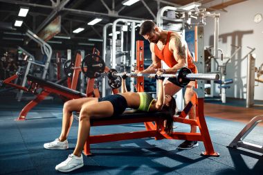 Sportif kız Yardımı salonunda kişisel onu antrenman ör ile ağırlık egzersizleri yapıyor.