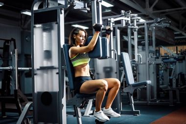 Genç ve sportif kadın göğüs kullanarak makine sinek