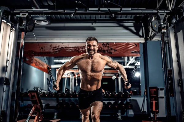 Culturista está trabajando en su pecho con cable cruzado en el gimnasio . — Foto de Stock