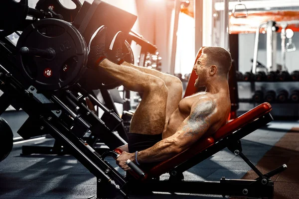 Bir Fitness kulübünde kullanan adam. Güçlü adam öğreniyor simülatörde bir egzersiz yapmak.