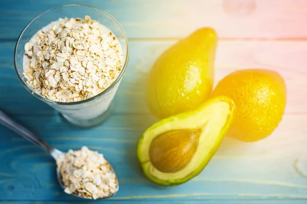 Sağlıklı gıda. Diyet Kahvaltı veya aperatif. Yoğurt, avokado, yulaf ezmesi gelen yeşil smoothies. Mavi ahşap masa üzerinde malzemelerle.