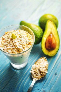 Sağlıklı gıda. Diyet Kahvaltı veya aperatif. Yoğurt, avokado, yulaf ezmesi gelen yeşil smoothies. Mavi ahşap masa üzerinde malzemelerle.
