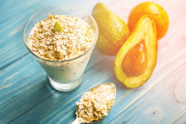 Sağlıklı gıda. Diyet Kahvaltı veya aperatif. Yoğurt, avokado, yulaf ezmesi gelen yeşil smoothies. Mavi ahşap masa üzerinde malzemelerle.