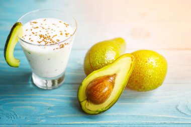 Sağlıklı gıda. Diyet Kahvaltı veya aperatif. Yoğurt, avokado, yulaf ezmesi gelen yeşil smoothies. Mavi ahşap masa üzerinde malzemelerle.