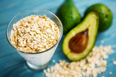 Sağlıklı gıda. Diyet Kahvaltı veya aperatif. Yoğurt, avokado, yulaf ezmesi gelen yeşil smoothies. Mavi ahşap masa üzerinde malzemelerle.