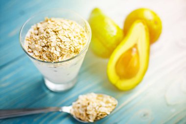 Sağlıklı gıda. Diyet Kahvaltı veya aperatif. Yoğurt, avokado, yulaf ezmesi gelen yeşil smoothies. Mavi ahşap masa üzerinde malzemelerle.