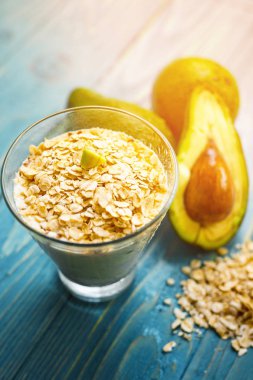 Sağlıklı gıda. Diyet Kahvaltı veya aperatif. Yoğurt, avokado, yulaf ezmesi gelen yeşil smoothies. Mavi ahşap masa üzerinde malzemelerle.