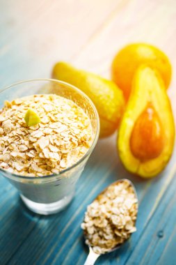 Sağlıklı gıda. Diyet Kahvaltı veya aperatif. Yoğurt, avokado, yulaf ezmesi gelen yeşil smoothies. Mavi ahşap masa üzerinde malzemelerle.