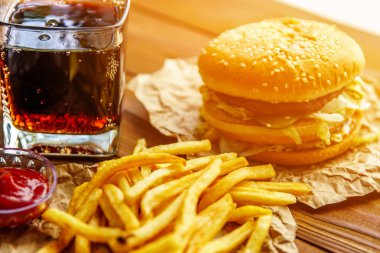 Burger patates kızartması ve kola ahşap arka plan üzerinde ile Kraft kağıt üzerinde