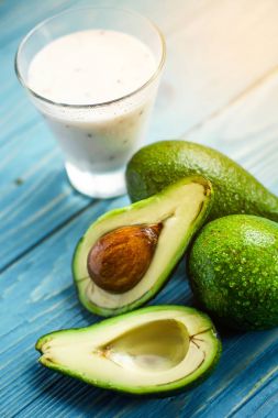 Sağlıklı gıda. Diyet Kahvaltı veya aperatif. Yoğurt, avokado, yulaf ezmesi gelen yeşil smoothies. Mavi ahşap masa üzerinde malzemelerle.