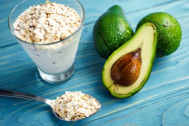 Sağlıklı gıda. Diyet Kahvaltı veya aperatif. Yoğurt, avokado, yulaf ezmesi gelen yeşil smoothies. Mavi ahşap masa üzerinde malzemelerle.