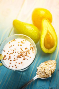Sağlıklı gıda. Diyet Kahvaltı veya aperatif. Yoğurt, avokado, yulaf ezmesi gelen yeşil smoothies. Mavi ahşap masa üzerinde malzemelerle.