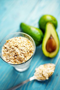 Sağlıklı gıda. Diyet Kahvaltı veya aperatif. Yoğurt, avokado, yulaf ezmesi gelen yeşil smoothies. Mavi ahşap masa üzerinde malzemelerle.