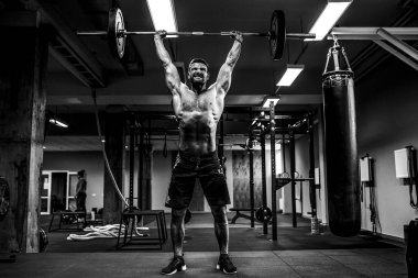 Modern fitness merkezinde kaslı bir fitness adamı halterle kafasına halteri indiriyor. Fonksiyonel eğitim.