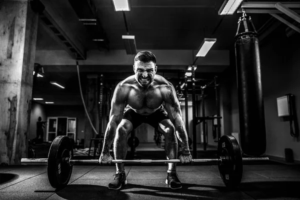 Modern fitness merkezinde kaslı bir fitness adamı halterle kafasına halteri indiriyor. Fonksiyonel eğitim.