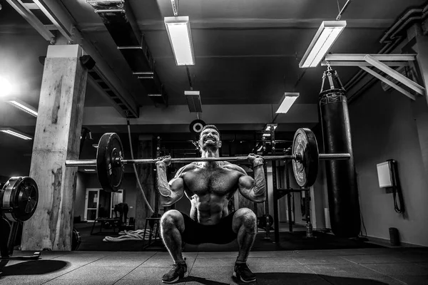 Een gespierde fitnessman die een halter over zijn hoofd tilt in een modern fitnesscentrum. Functionele opleiding. — Stockfoto