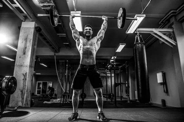 Homem de fitness muscular fazendo deadlift um sino sobre sua cabeça no moderno centro de fitness. Treinamento funcional. — Fotografia de Stock