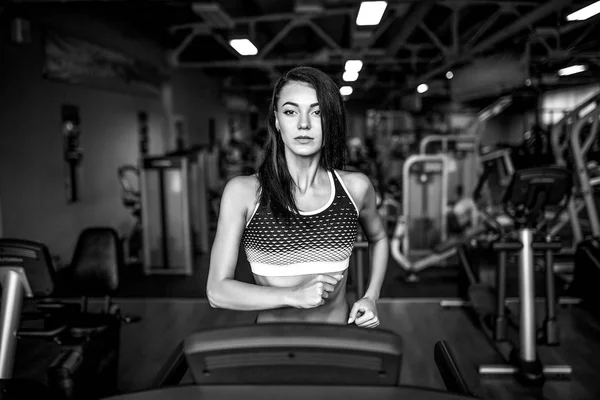 年轻的健身女人做有氧运动在健身房的跑步机上. — 图库照片
