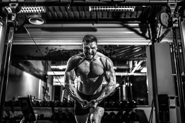 Bodybuilder werkt op zijn borst met cross-over kabel in gym. — Stockfoto
