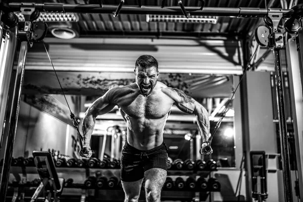 Bodybuilder arbetar på bröstet med kabel delningsfilter i gym. — Stockfoto