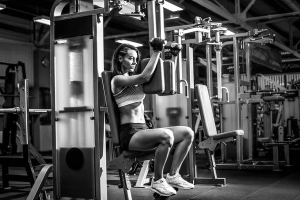 Mujer joven y deportiva usando la máquina de la mosca pectoral — Foto de Stock