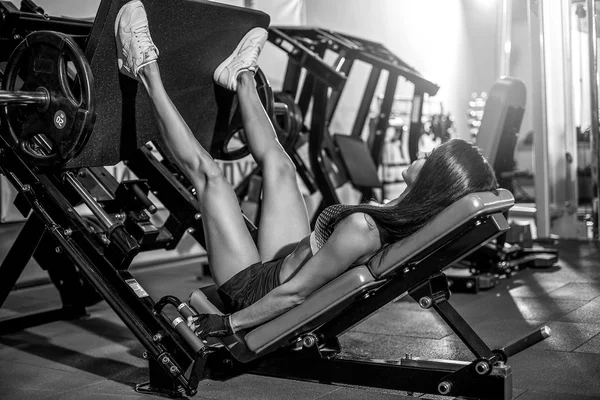 Kadın fitness eğitim bir bacak uzatma itme makinede ağırlıkları ile yapıyor