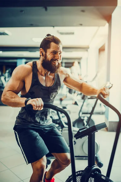 spor salonunda egzersiz bisikleti kullanan genç adam. Crossfit spor salonunda kardiyo egzersiz için hava bisiklet kullanarak fitness erkek.